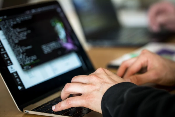 A pair of hands working on a laptop.