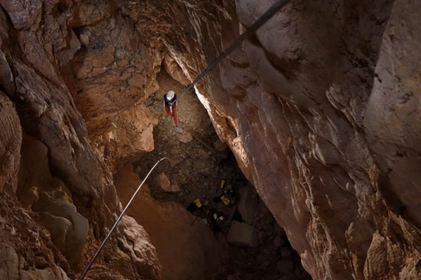 climber descending into calcite cave