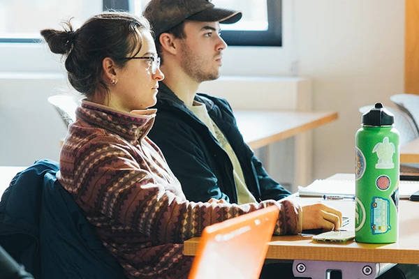 Two students sitting at desks in a classroom.
