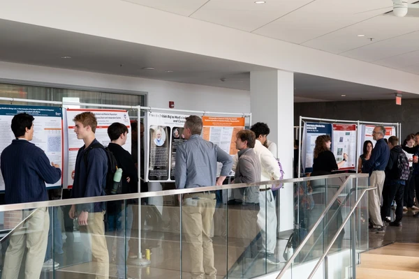 A group of students milling about a poster fair.