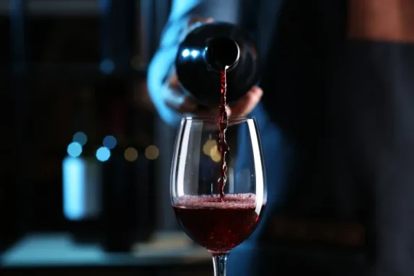 Dramatically lit wine bottle pouring red wine in a glass. 