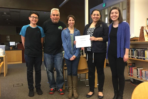 Yahir Santillan-Guzman (far left), then a student at The Dalles High School, received his Juntos program completion certificates from Andrea Flores (middle), with his parents and another Juntos volunteer present.