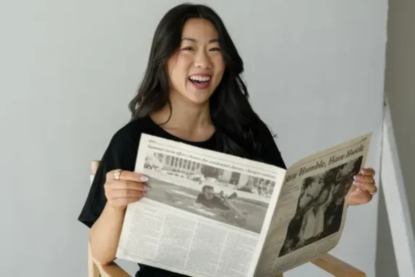 Marisa Chen holding a newspaper and smiling