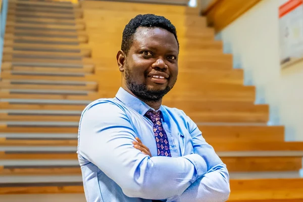 Sunday A. Adetunji, MD poses with his arms crossed, wearing a light blue collared shirt.