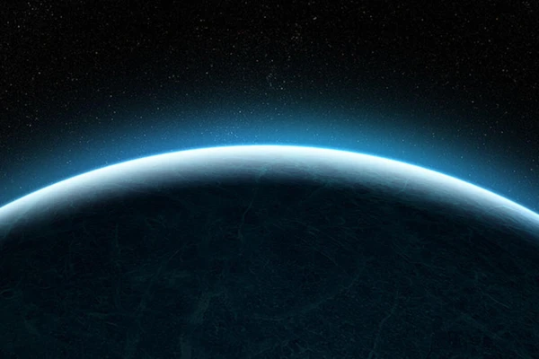 Dramatic image of light glowing from behind the curve of a planet in space.