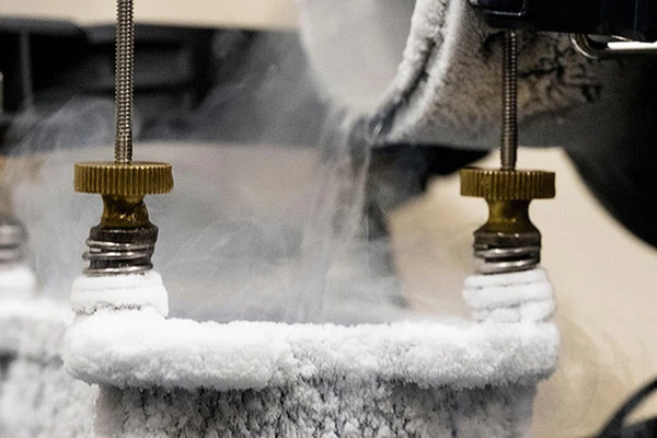 Liquid nitrogen is poured over an external computer part to enhance cooling; the part is entirely frosted over.