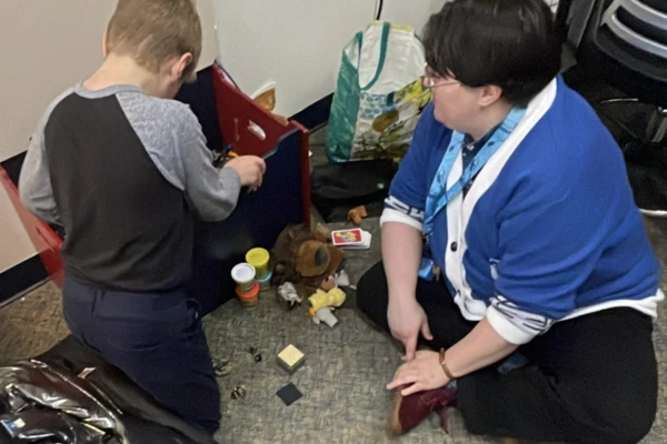 Child playing next to teacher