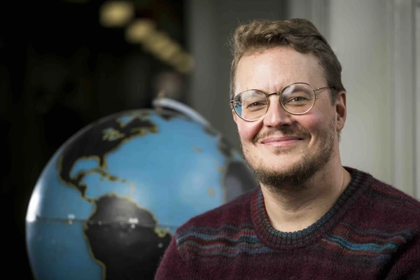 Jamon Van Den Hoek sits in front of a globe.
