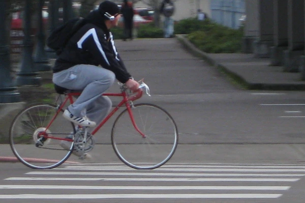 A student rides a red bike around campus.